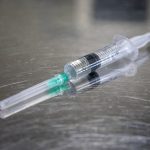 A syringe laying on a stainless steel table
